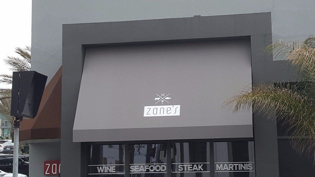Gray storefront with a large awning, sign reading “Vito,” and windows labeled wine, seafood, steak, and martinis.