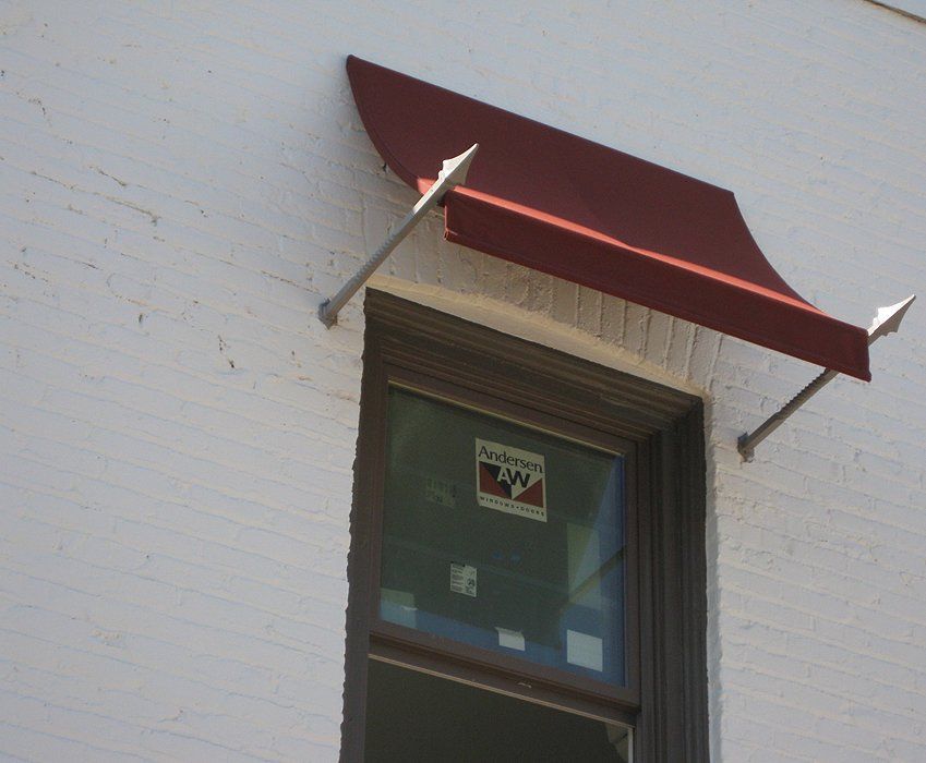 Red awning above a window on a white brick building