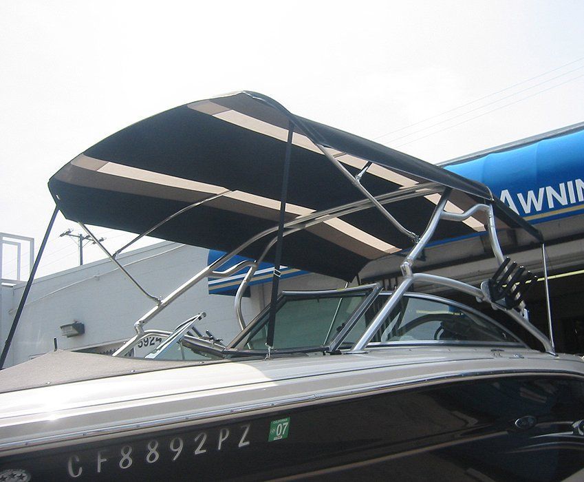 Black-and-white motorboat with a striped canopy at a dock, viewed from the front