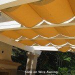 Yellow retractable awning with wavy fabric slats over a patio or walkway