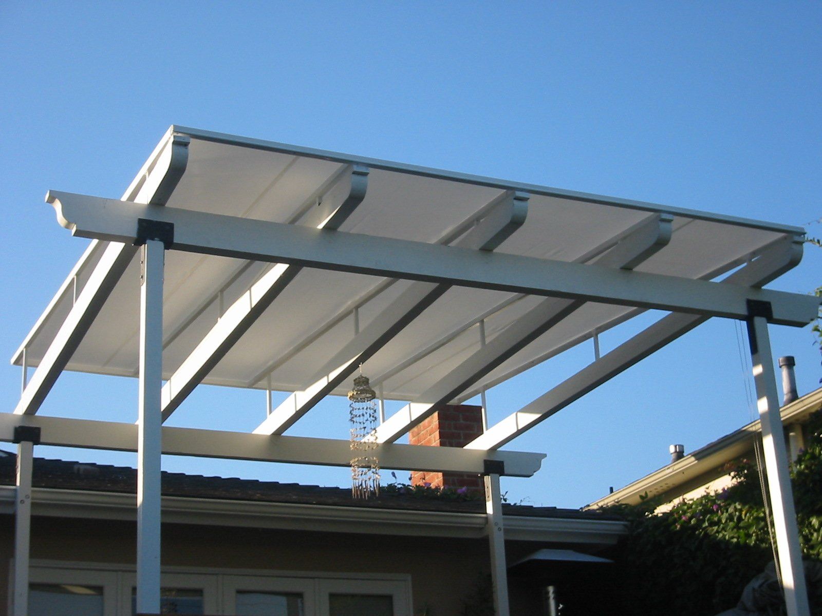 White metal carport canopy with translucent roof panels against a blue sky