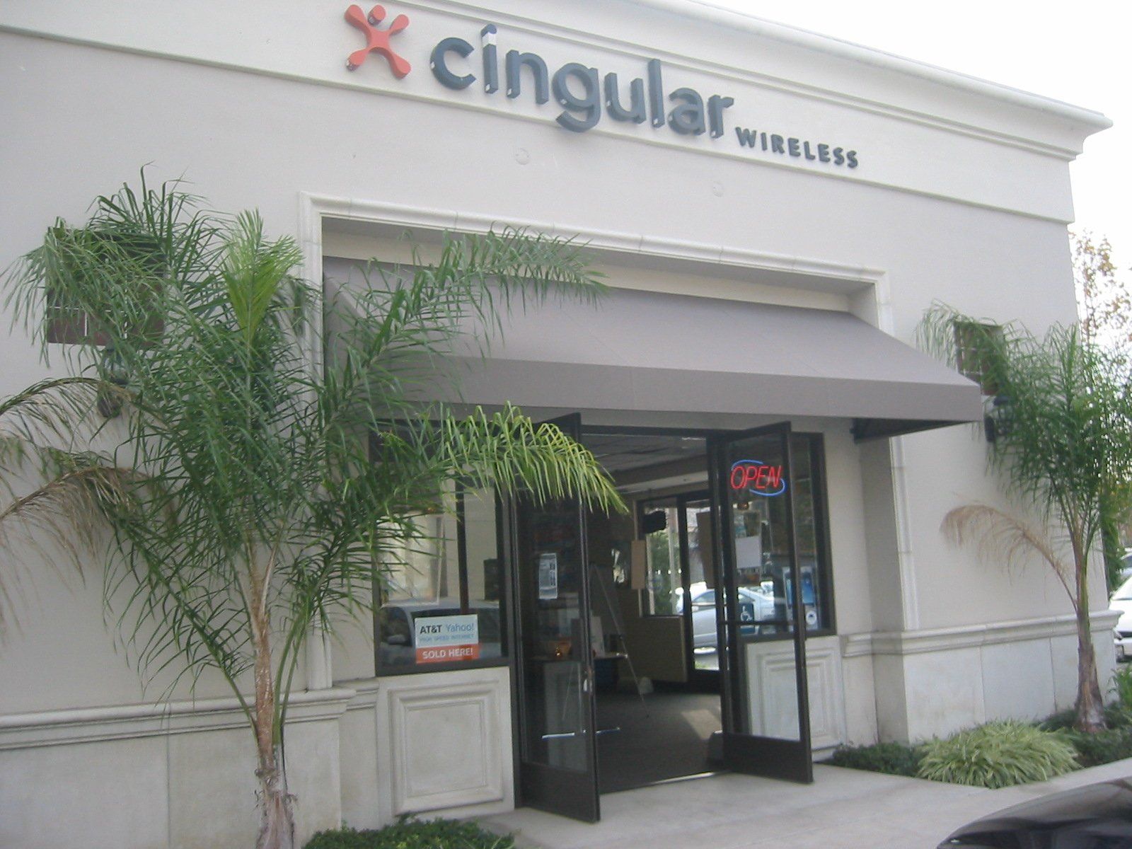 Cingular Wireless storefront with glass entrance, awning, and palm trees outside