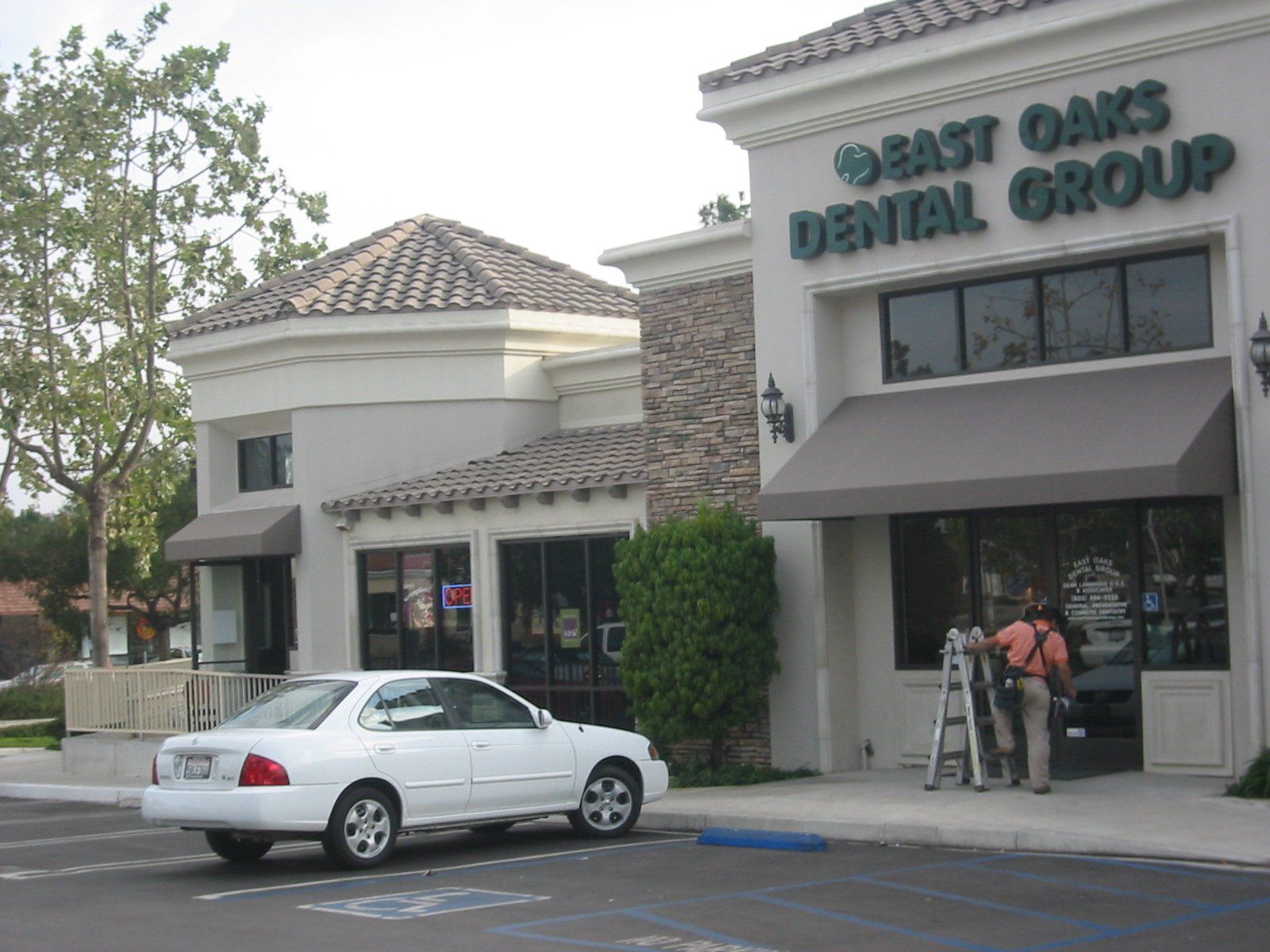 Exterior of Great Oaks Dental Group with a white sedan parked outside and workers at the entrance