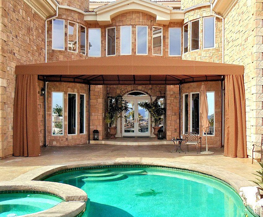 Luxury stone house with arched windows and a turquoise pool in the foreground