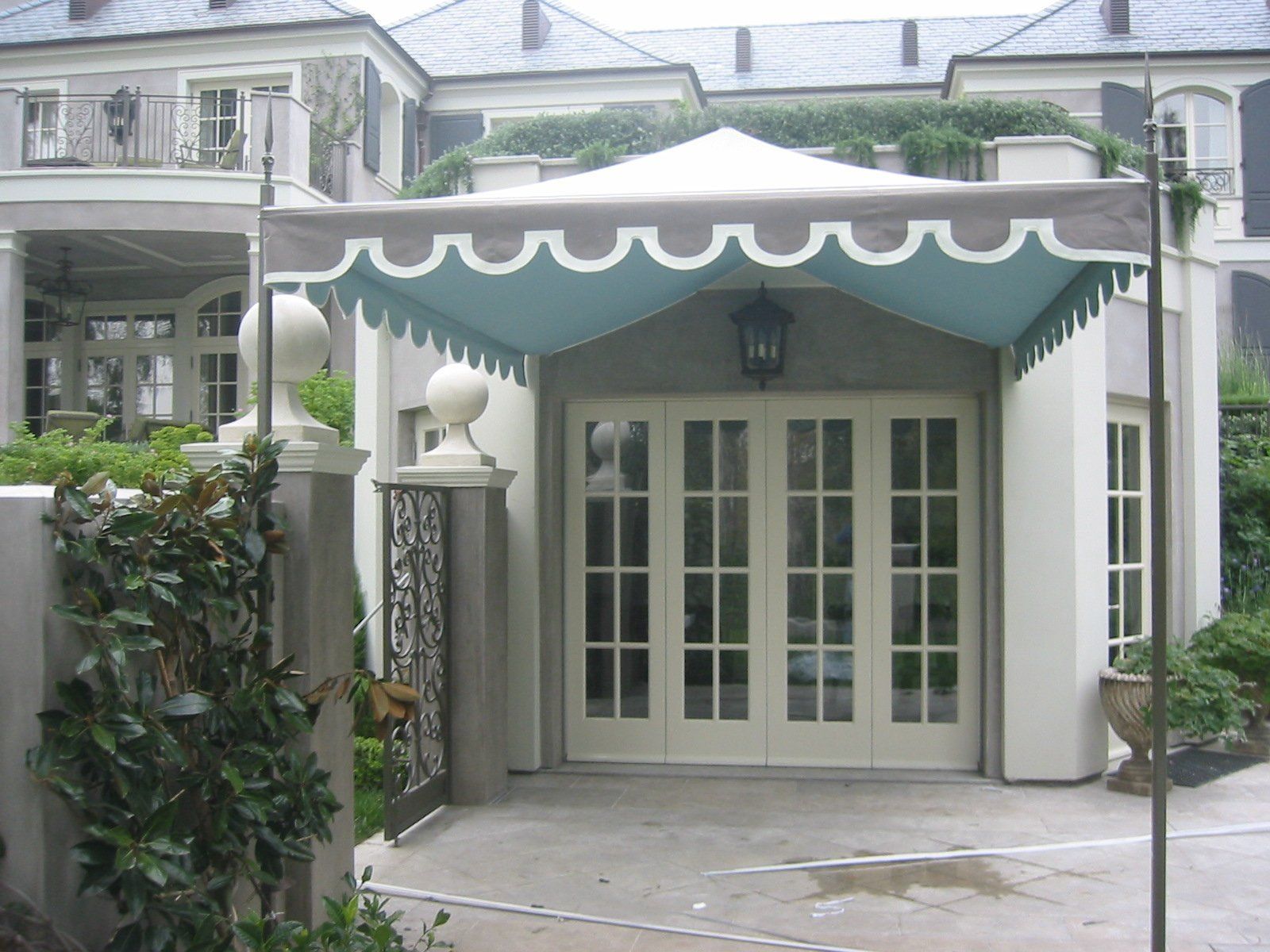 Covered entrance with scalloped awning and French doors at a white building