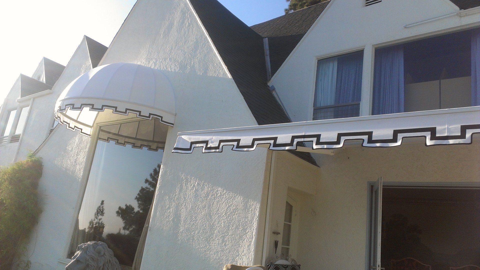 White stucco building with arched windows and dark geometric roof accents in bright sunlight