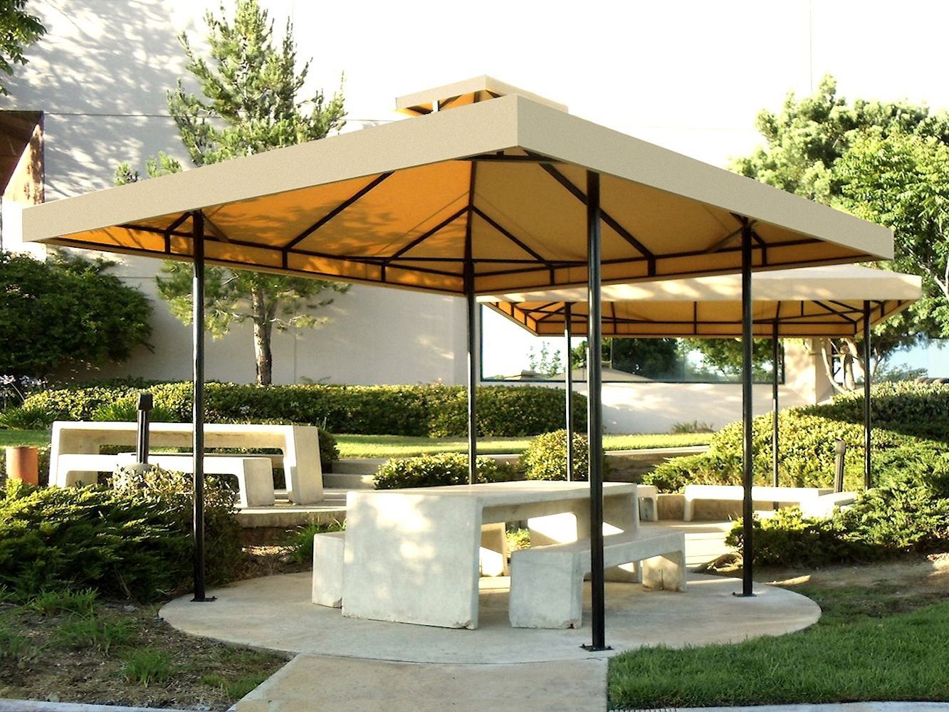 Outdoor gazebo with a tan canopy, black posts, and stone benches in a landscaped garden