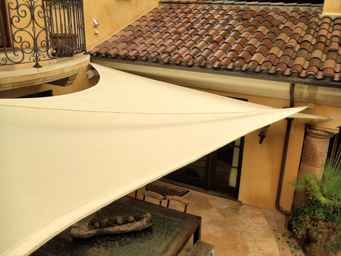 Beige patio canopy over a courtyard with tiled roofs and stone flooring