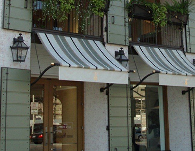 Storefront with white-and-gray striped awnings and shuttered windows on a city street