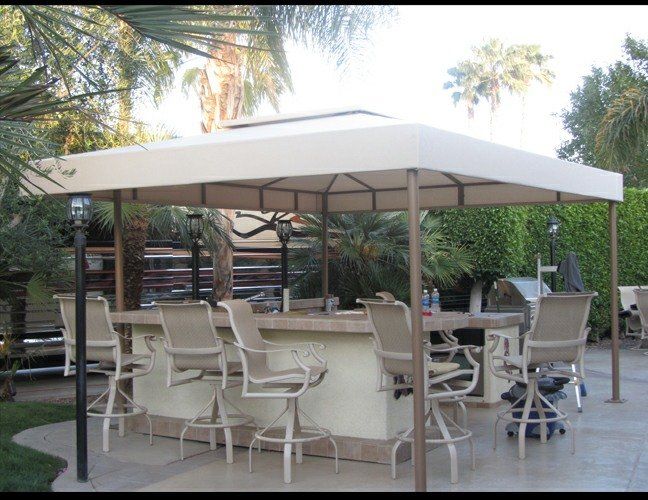 Outdoor patio bar with white cabana, tables, and chairs in a garden setting