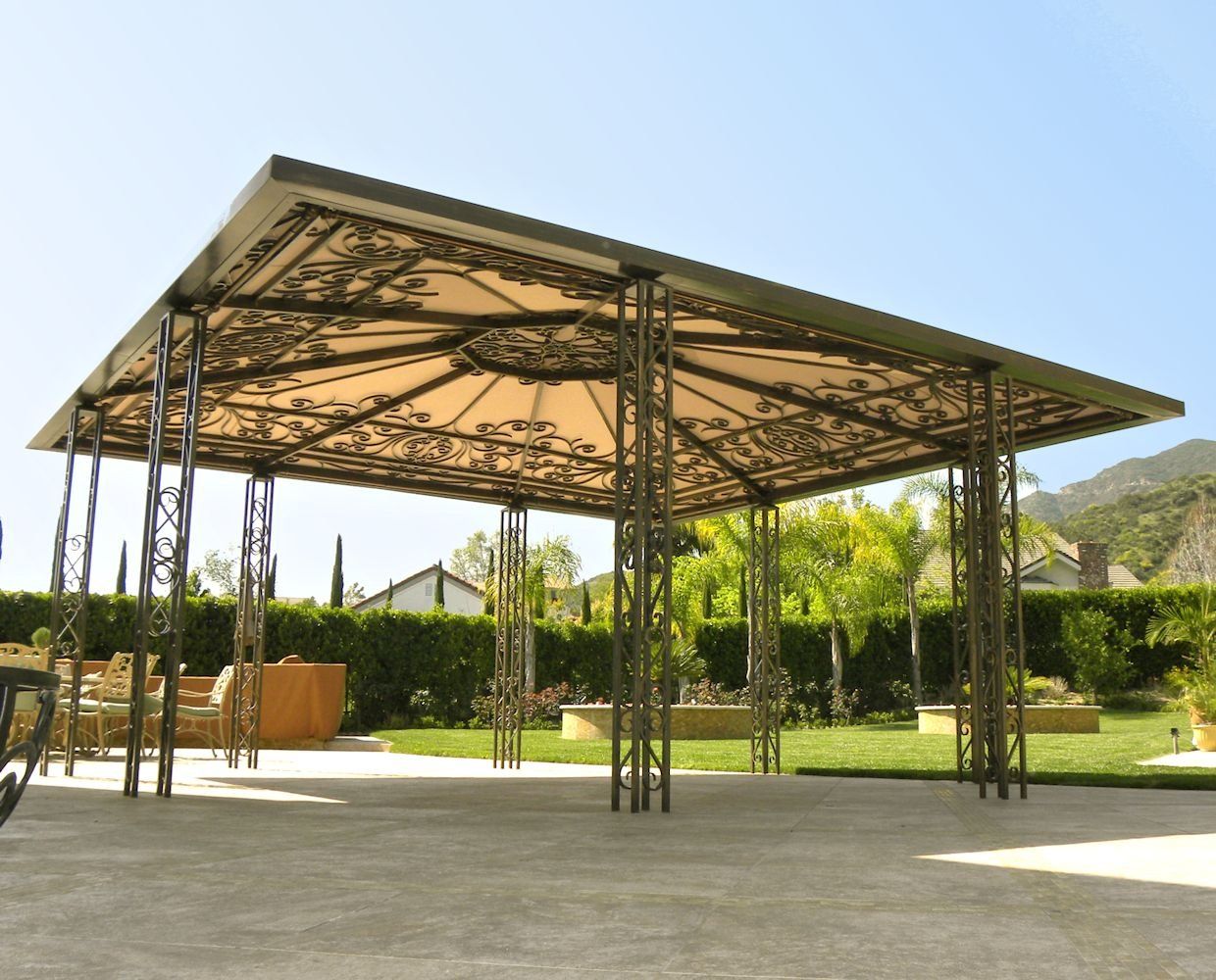 Open-air pavilion with metal roof and supports in a sunny landscaped park