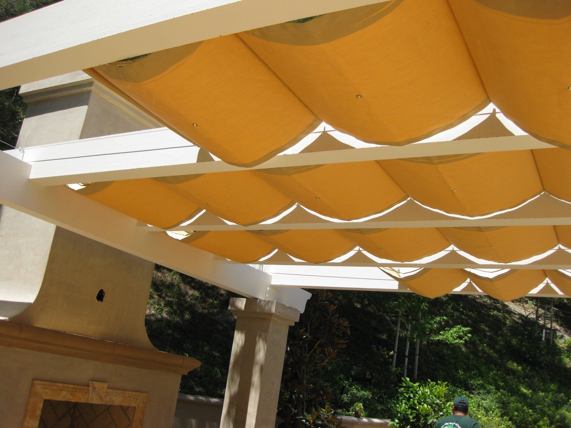 Orange awning panels over a white pergola in a sunny outdoor patio area