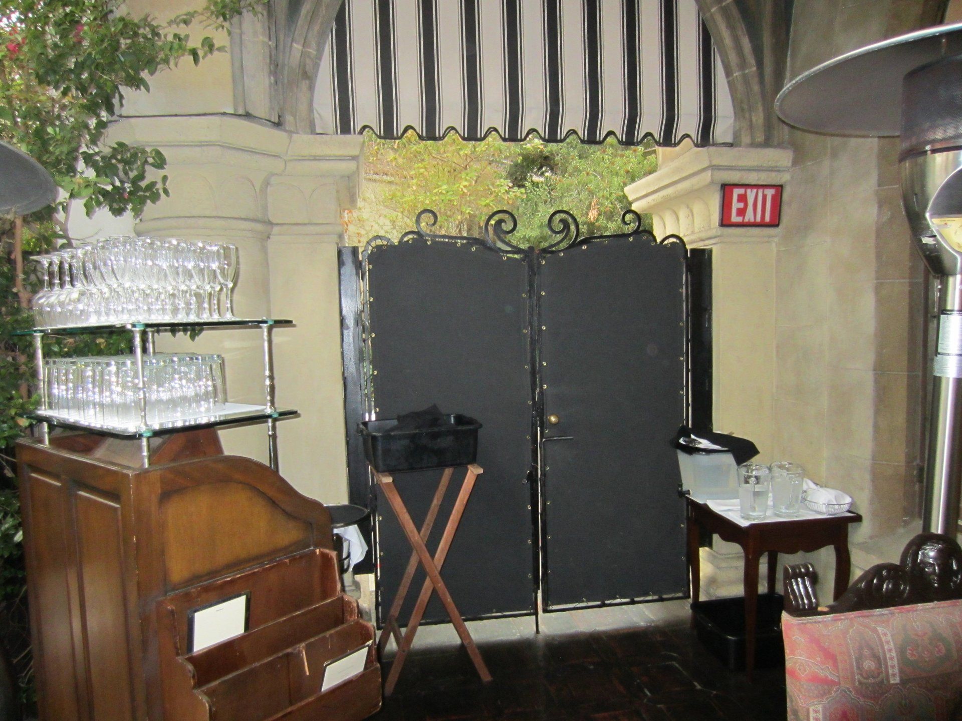 Restaurant interior with double doors, EXIT sign, piano, and stacked glasses on shelves