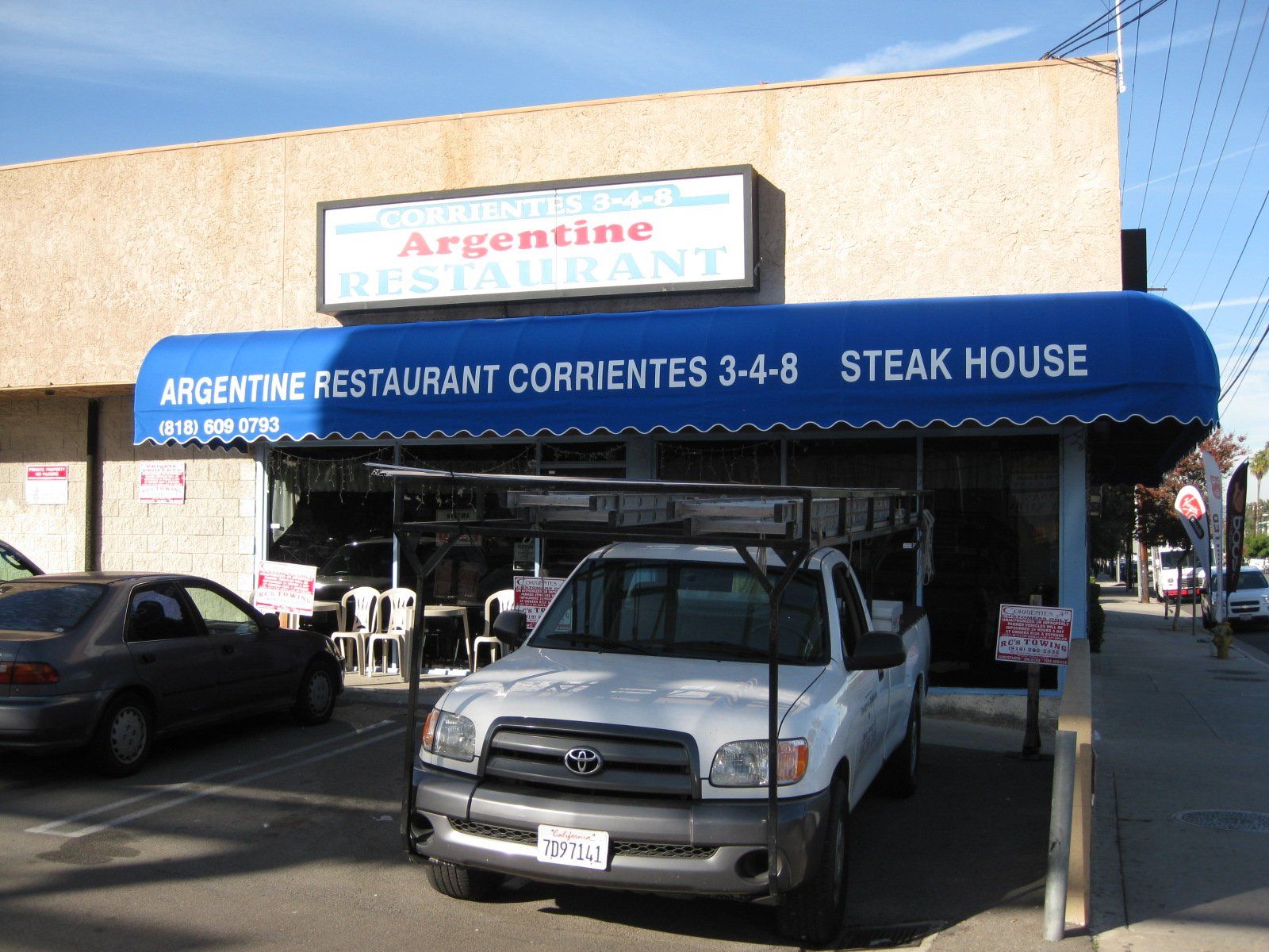 Silver pickup under blue awning at Argentina Restaurant steakhouse storefront