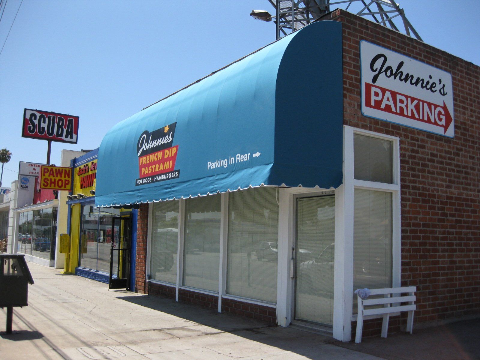 Street view of a blue-awning storefront with a “Johnnie’s Parking” sign on the brick wall