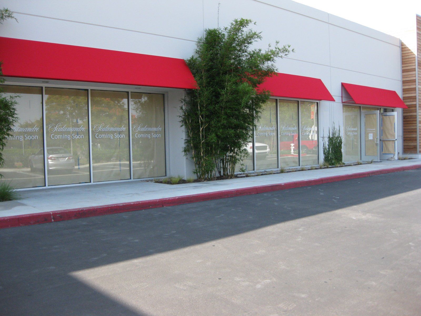 Storefront with red awnings and large windows along a sidewalk