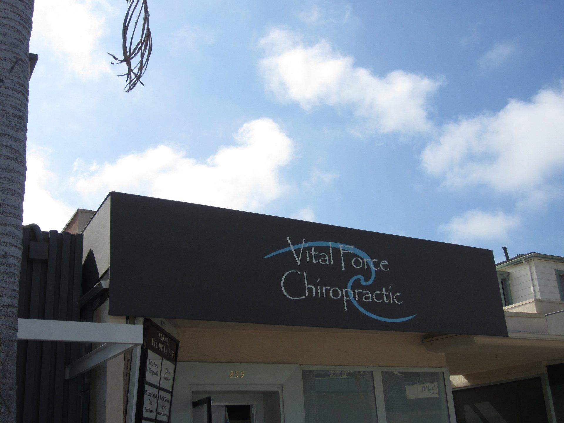 Exterior of Vital Life Chiropractic office with black sign and blue sky above