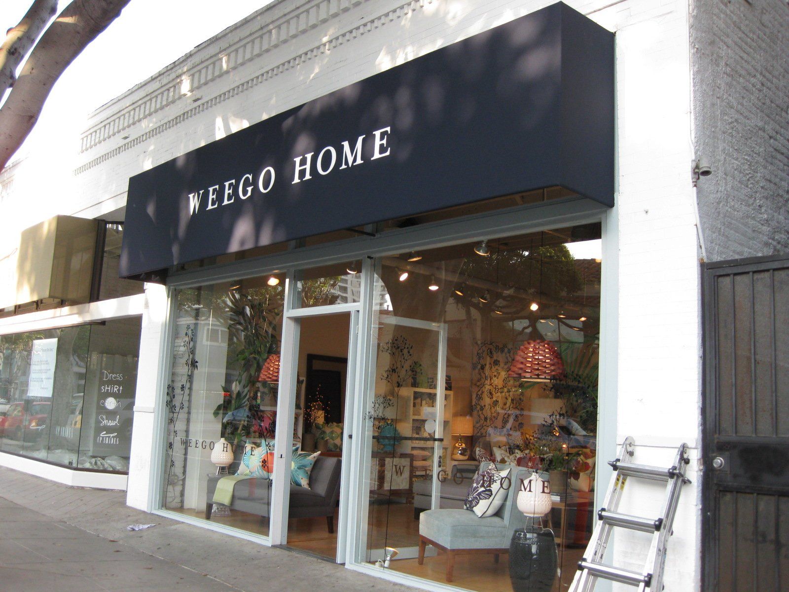 Storefront of a home decor shop with a black awning and large glass windows on a city street
