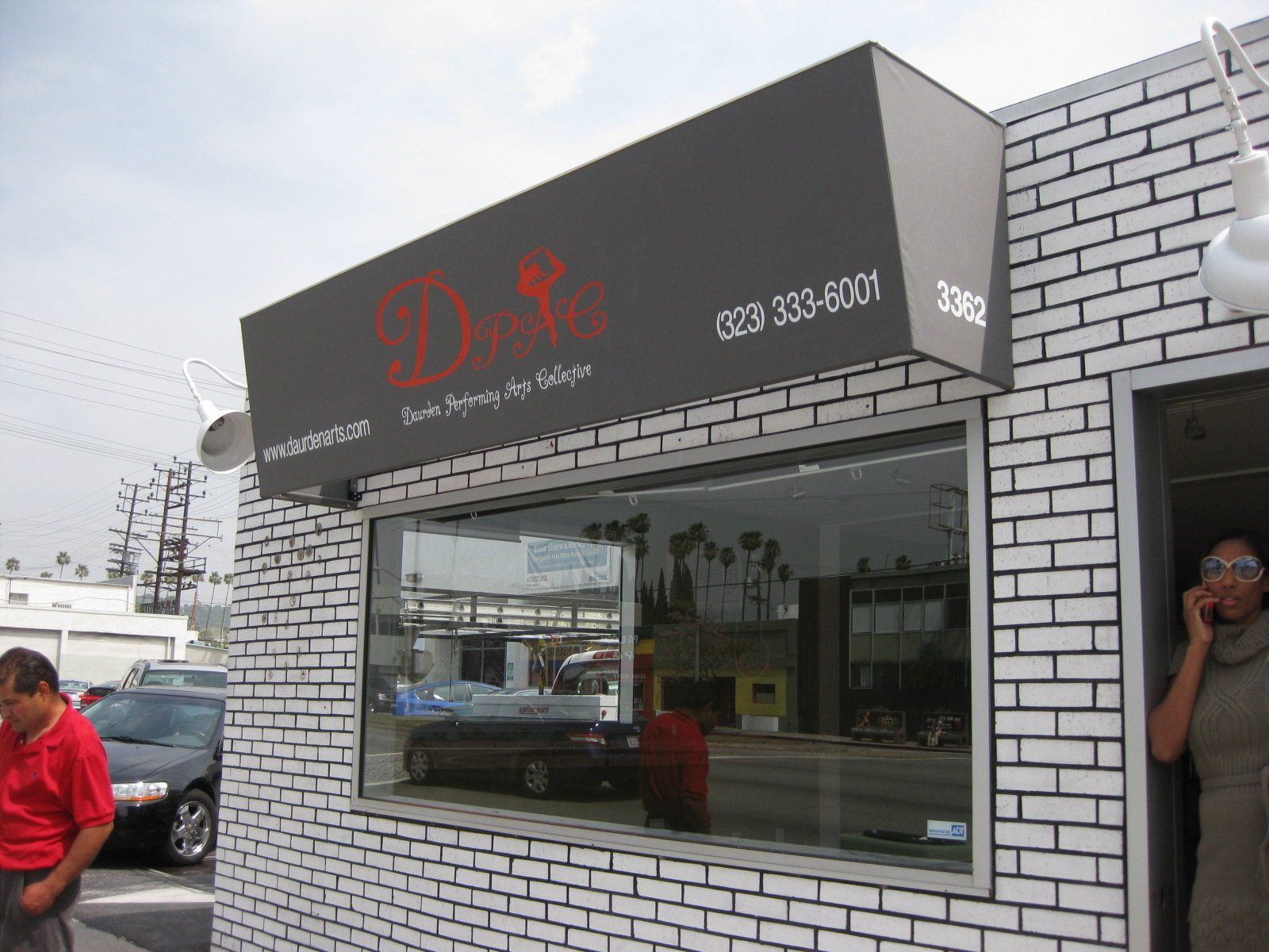 Black storefront with red signage and large window on a city street