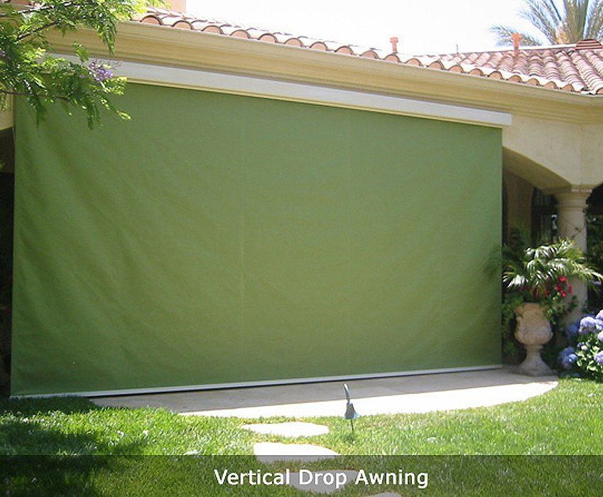 Green vertical drop awning covering a patio opening on a house exterior.
