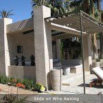 Patio with slide-on wire awning, beige columns, and lounge chairs in a sunny garden area