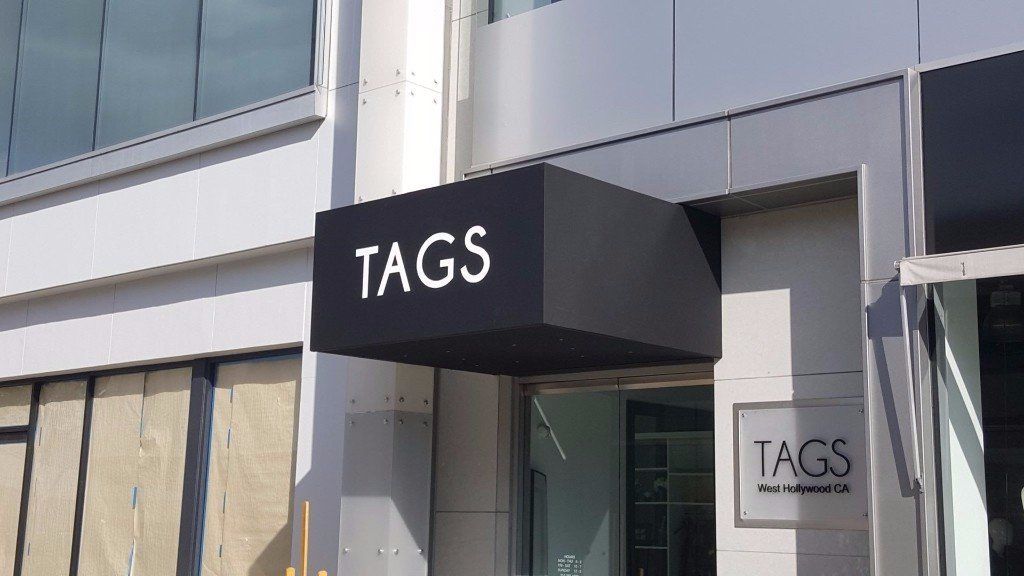 Storefront entrance with a black awning labeled “TAGS” on a modern building.