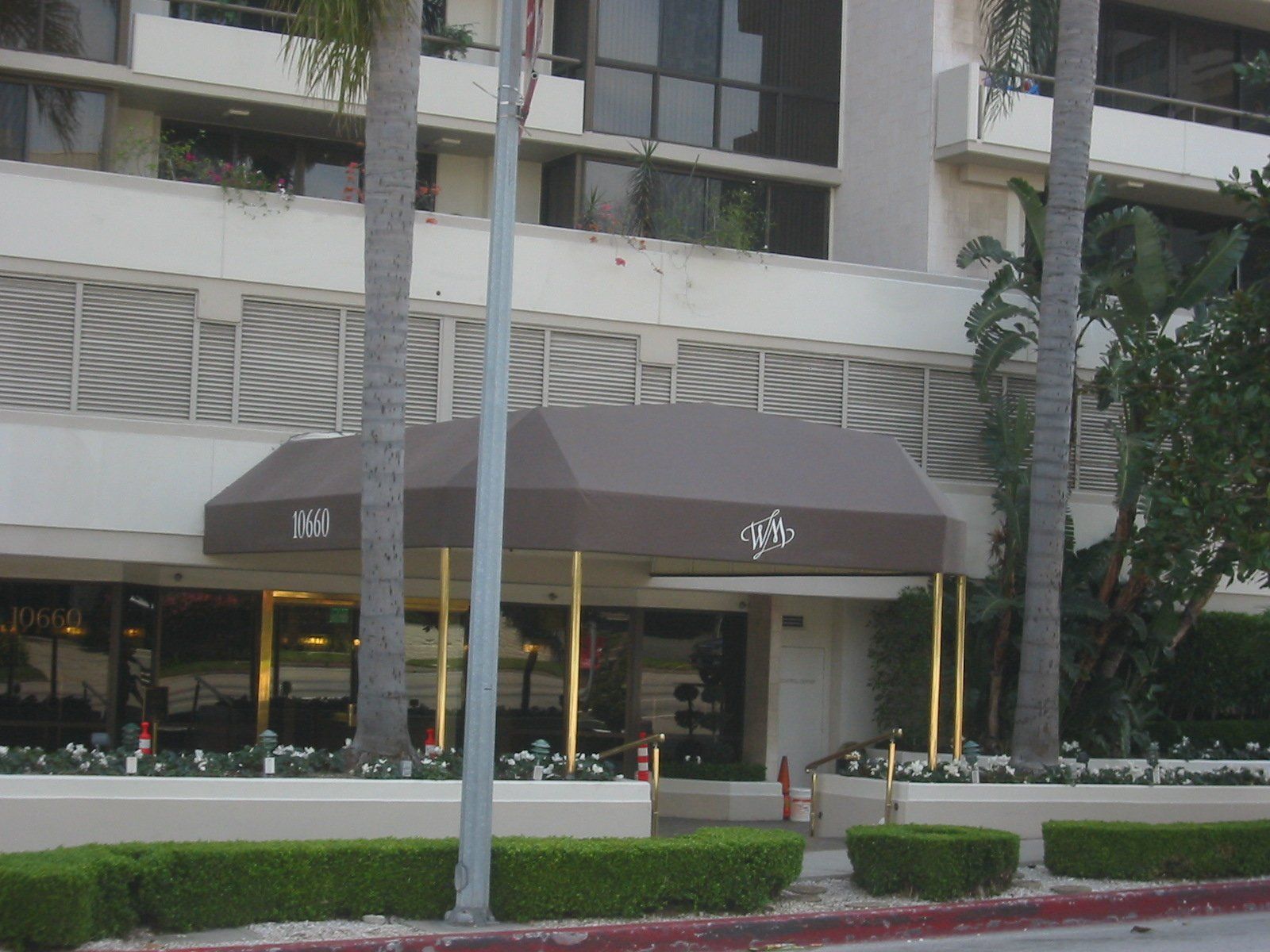 Street-level storefront with brown awnings in front of a modern apartment building.