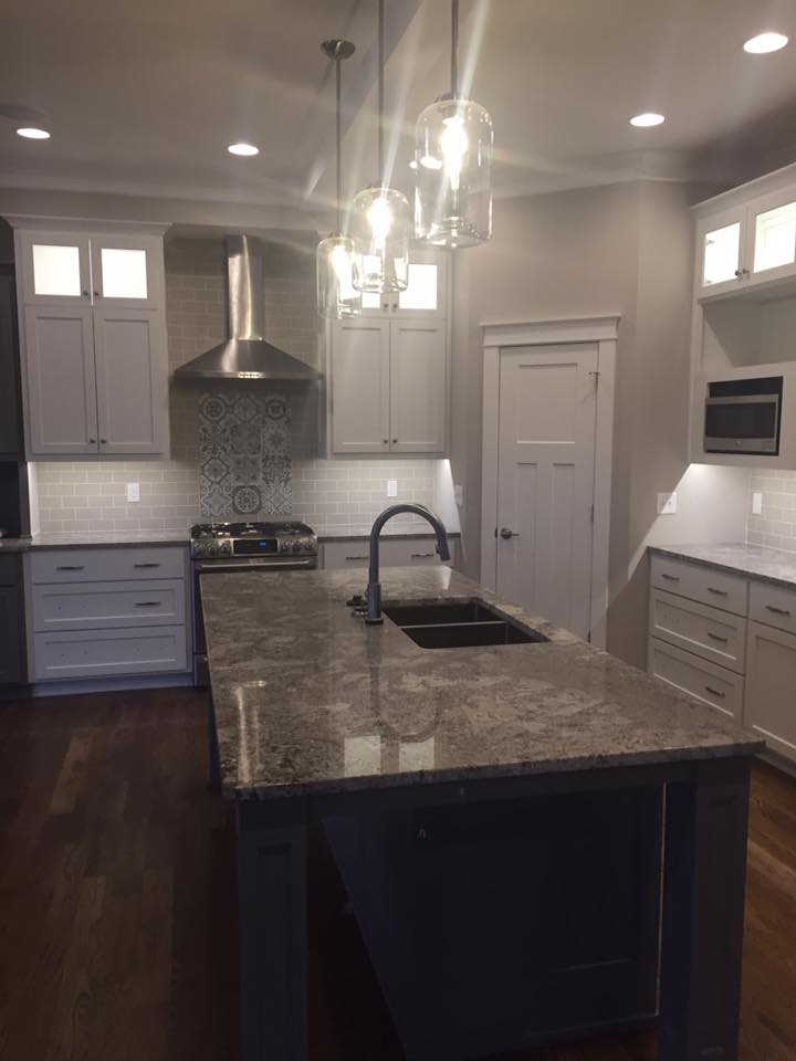 A kitchen with white cabinets , granite counter tops , a sink and a stove.