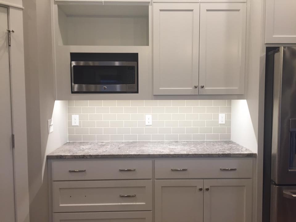 A kitchen with white cabinets , granite counter tops , stainless steel appliances and a microwave.