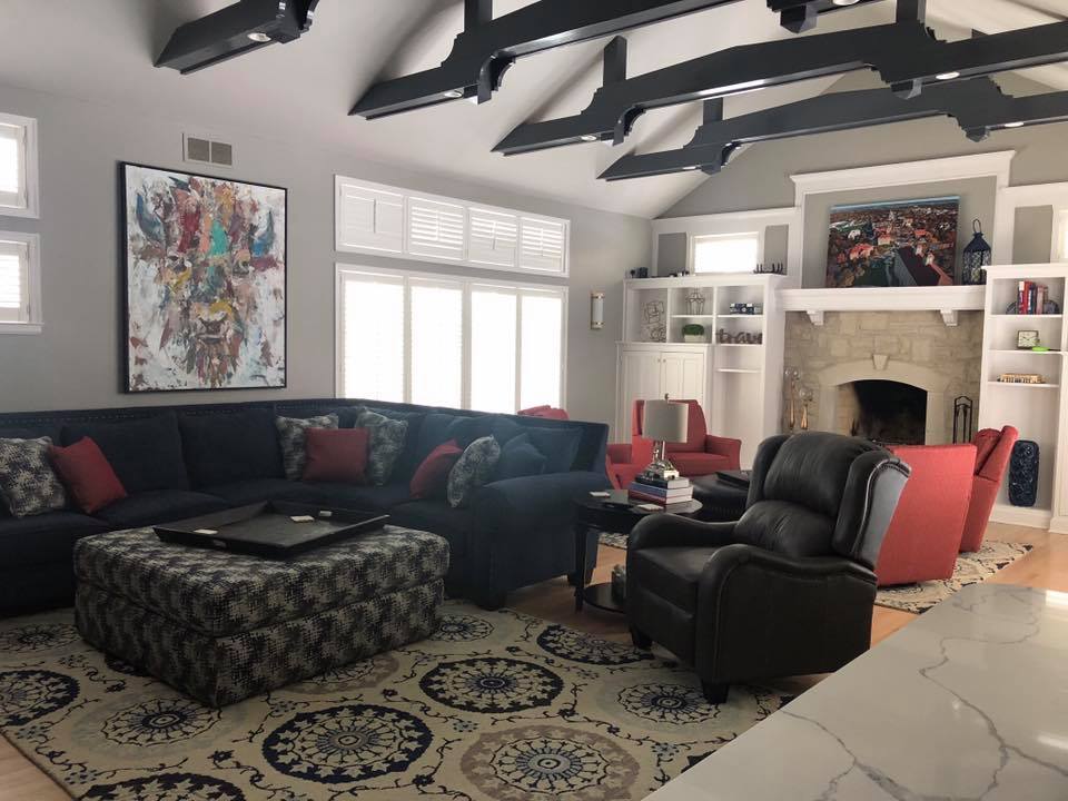 Living room with gray walls, dark sectional sofa, fireplace, and patterned rug.