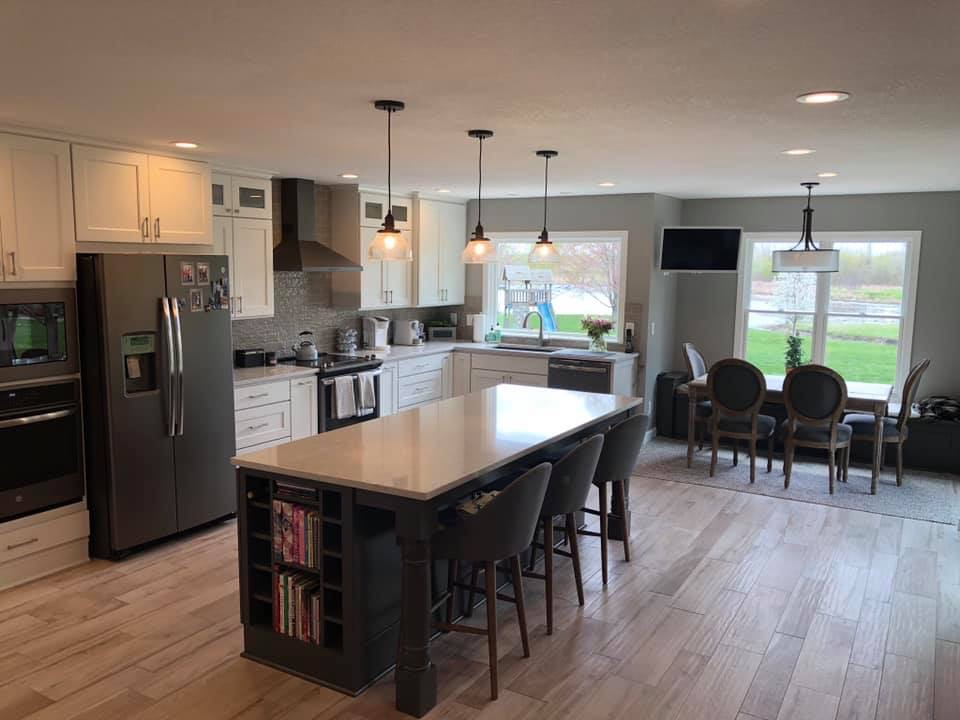 Modern kitchen with white cabinets, stainless steel appliances, large island with seating, and dining area.