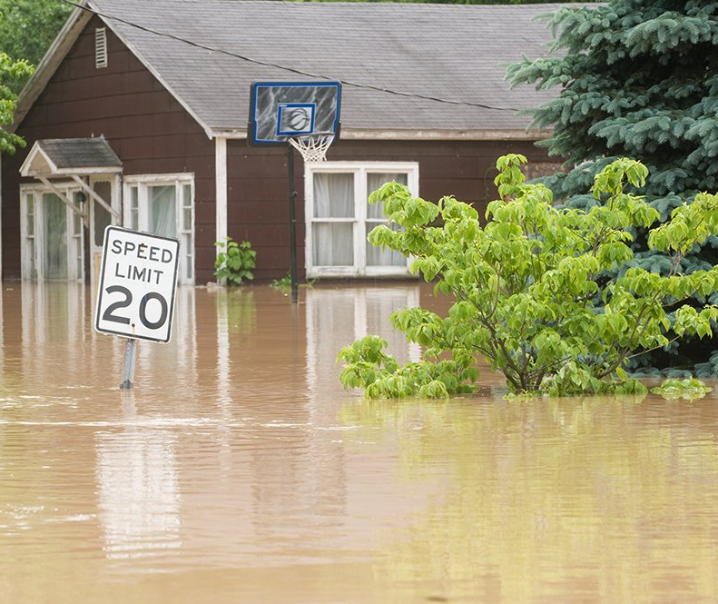 house, street, and lawn flooded with dirty water
