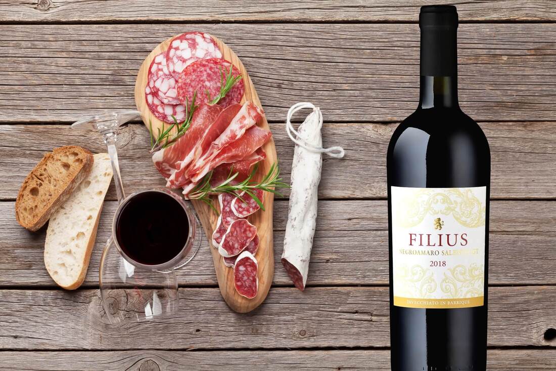 WEINFELS Rotwein Filius mit Wurstwaren auf Holzhintergrund