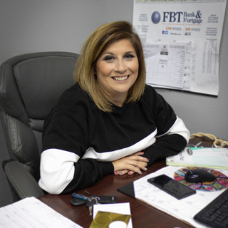 woman sitting at desk with arms crossed and smiling
