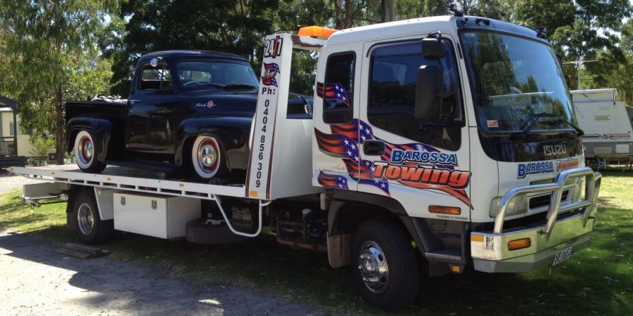 A tow truck moving cars and farm machinery in the Barossa valley