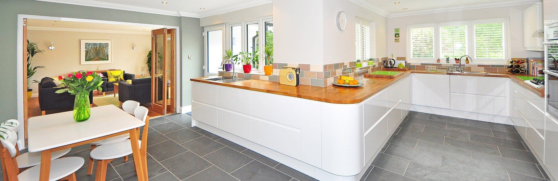 A bright, modern kitchen with white cabinets and a wooden countertop.