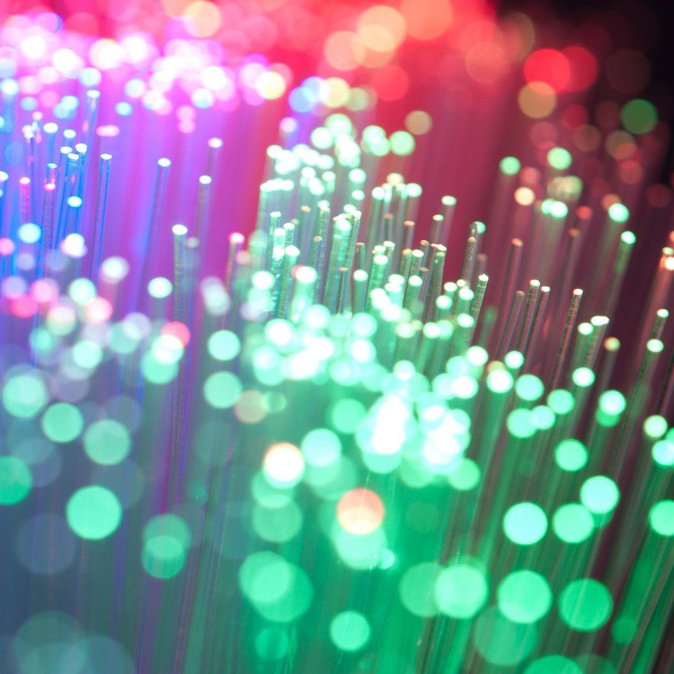 Close-up of illuminated fiber optic cables emitting various colors: green, blue, and red.