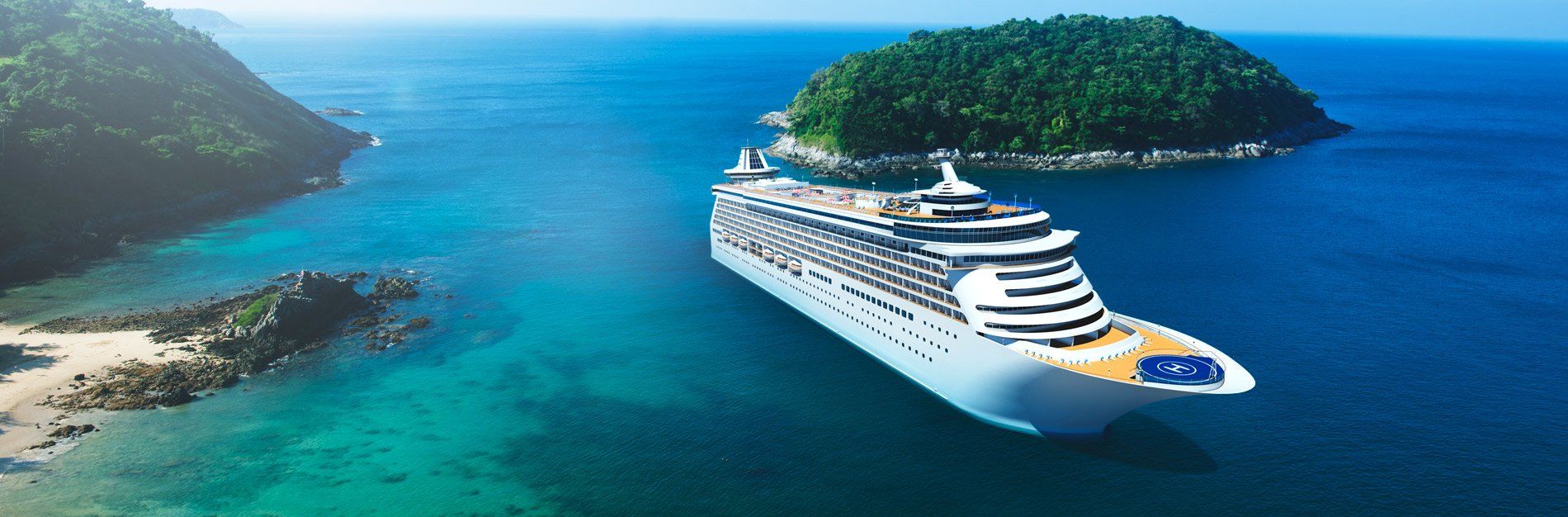 Cruise ship sailing near a tropical island with turquoise water.