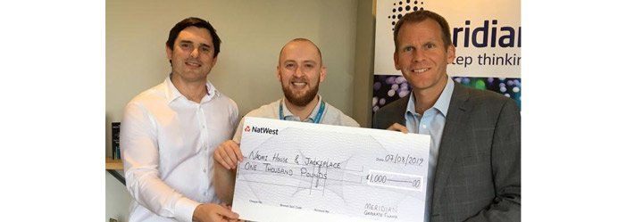 Three men holding a large check with text: 