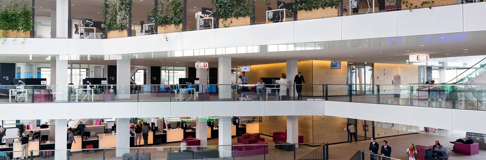 Multi-story office interior with white walls, glass railings, and people.