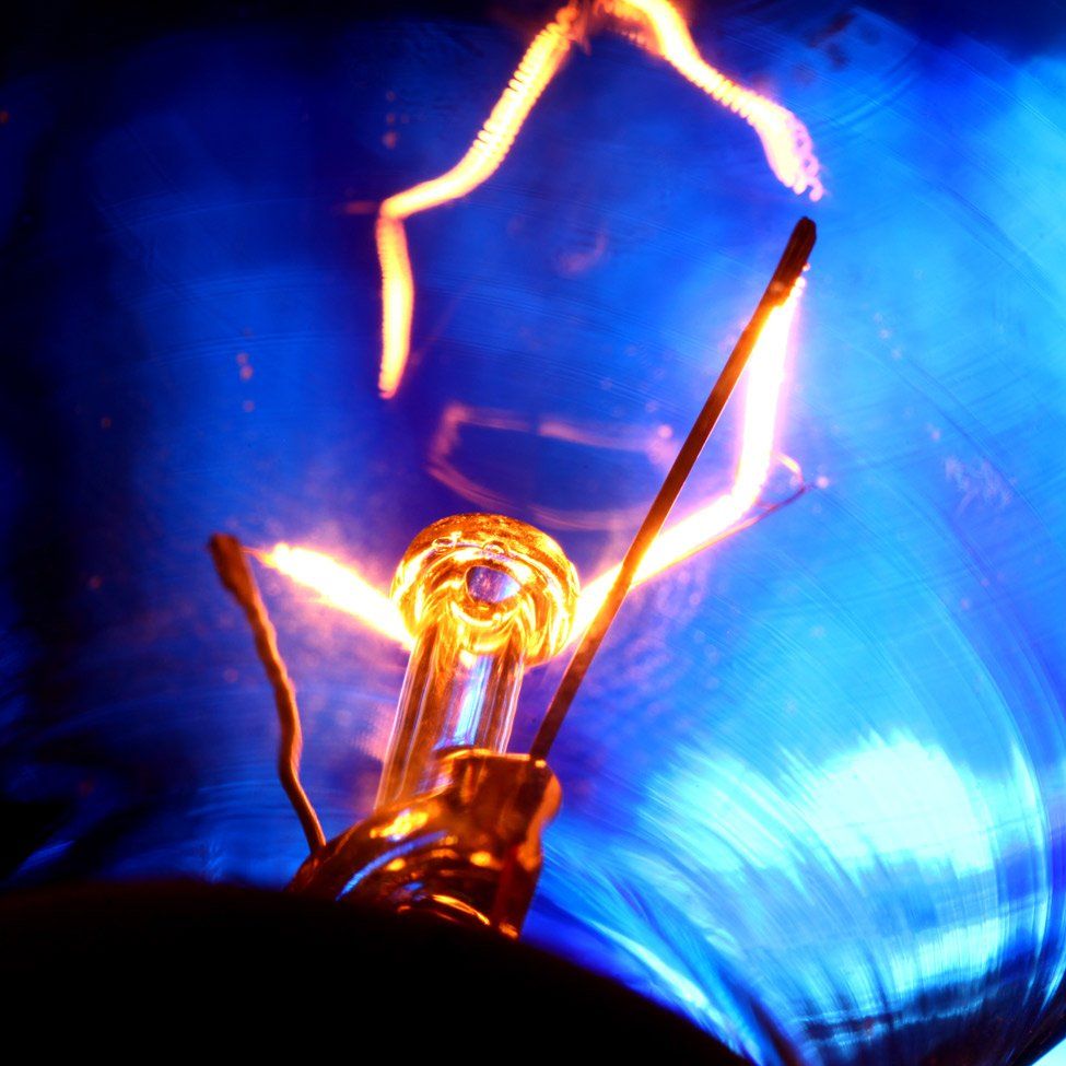 Glowing lightbulb filament against a blue background.
