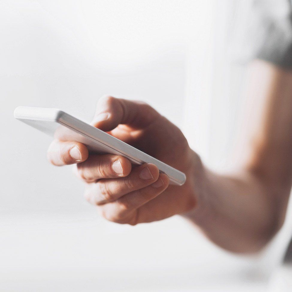 Person holding a white smartphone, likely using it; close-up shot.