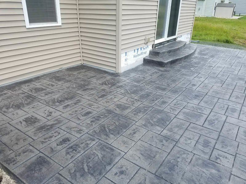 A patio in front of a house with steps leading to it.
