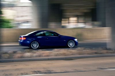 A dark blue BMW driven at pace through a city