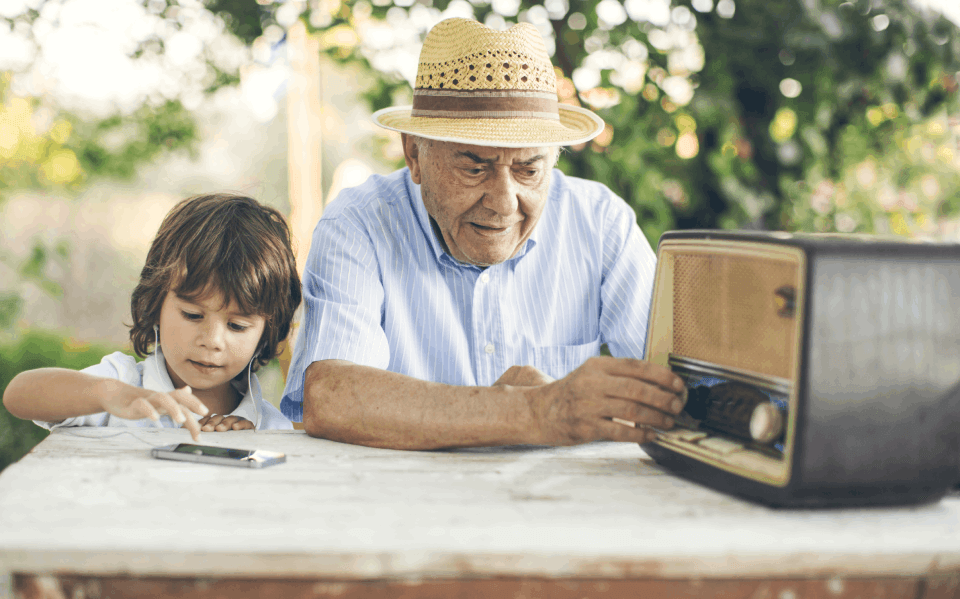 Nonno con apparecchio acustico auricolare e nipote che ascoltano la radio