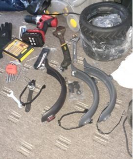 A bunch of bike tools are on the floor including a drill