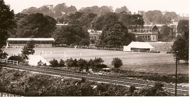 A black and white photo of a field with a building in the background
