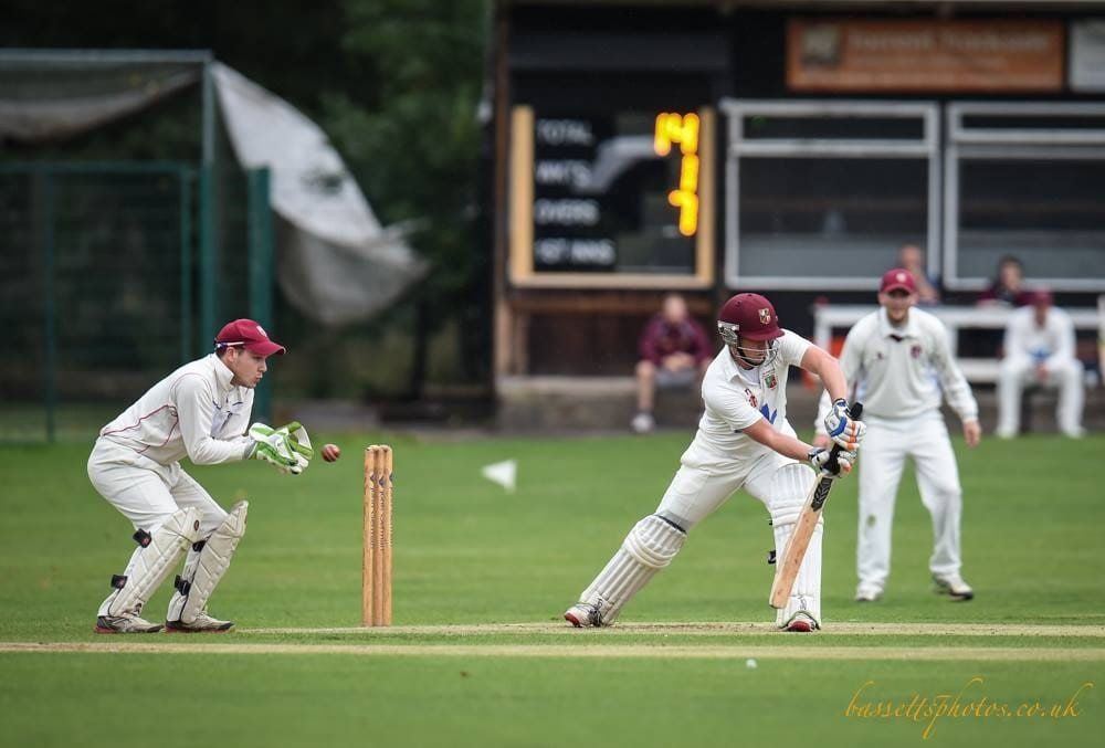 A group of men are playing a game of cricket on a field.