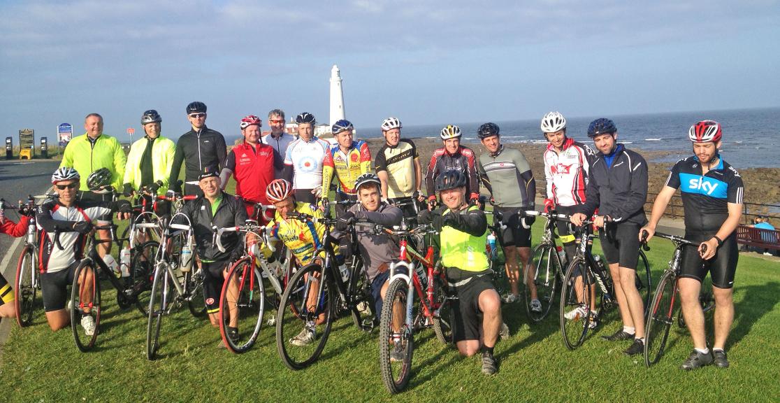 A group of people are posing for a picture with their bikes.