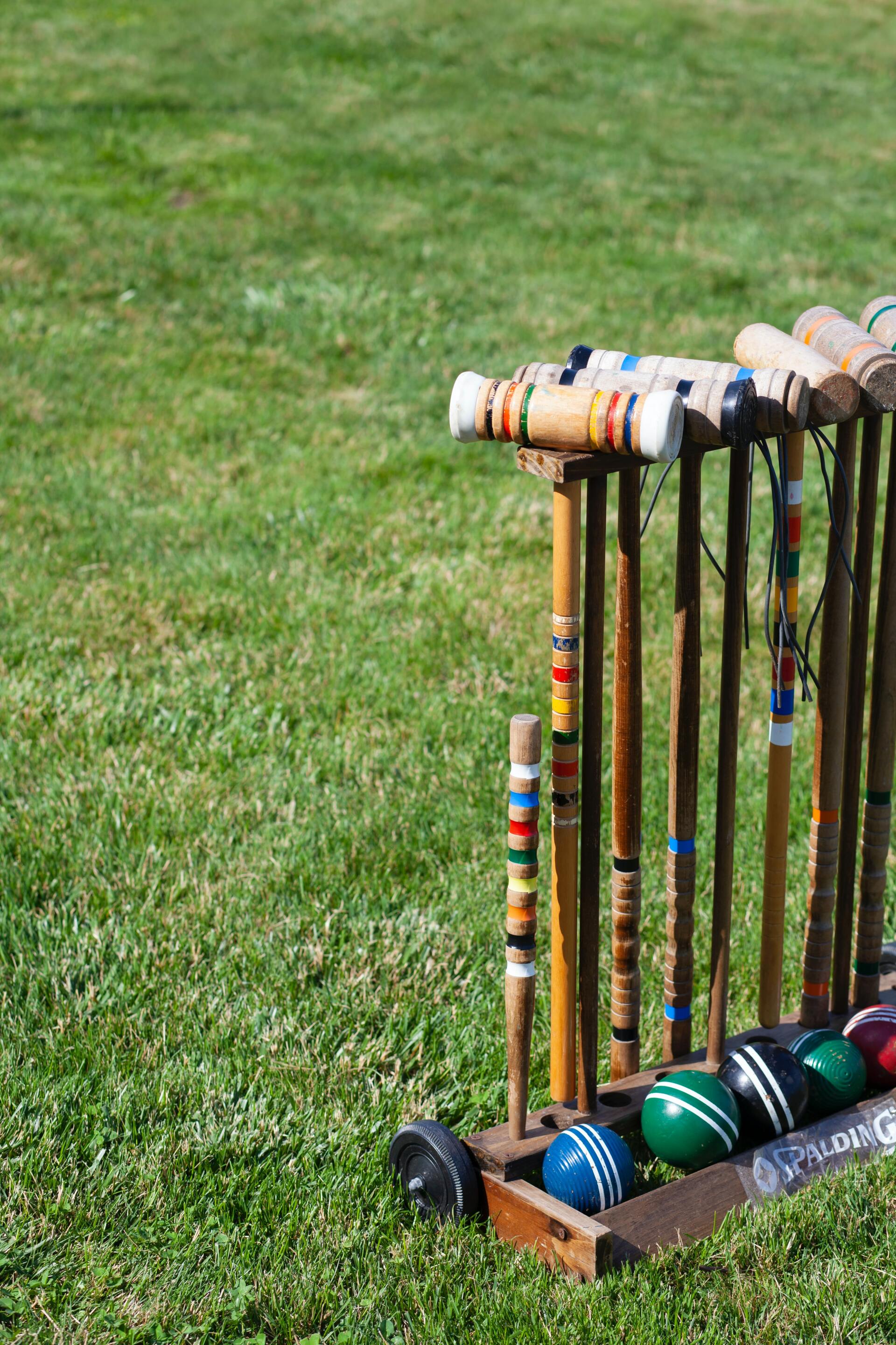 A croquet set is sitting on top of a wooden stand in the grass.